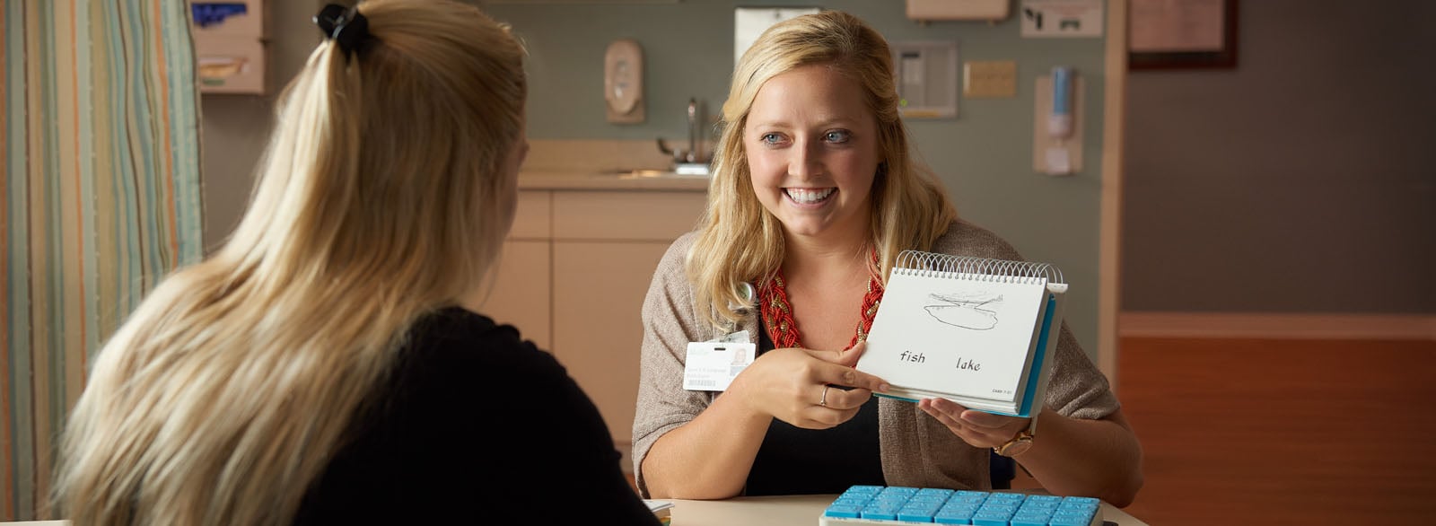 Speech therapist showing flash cards to a patient.