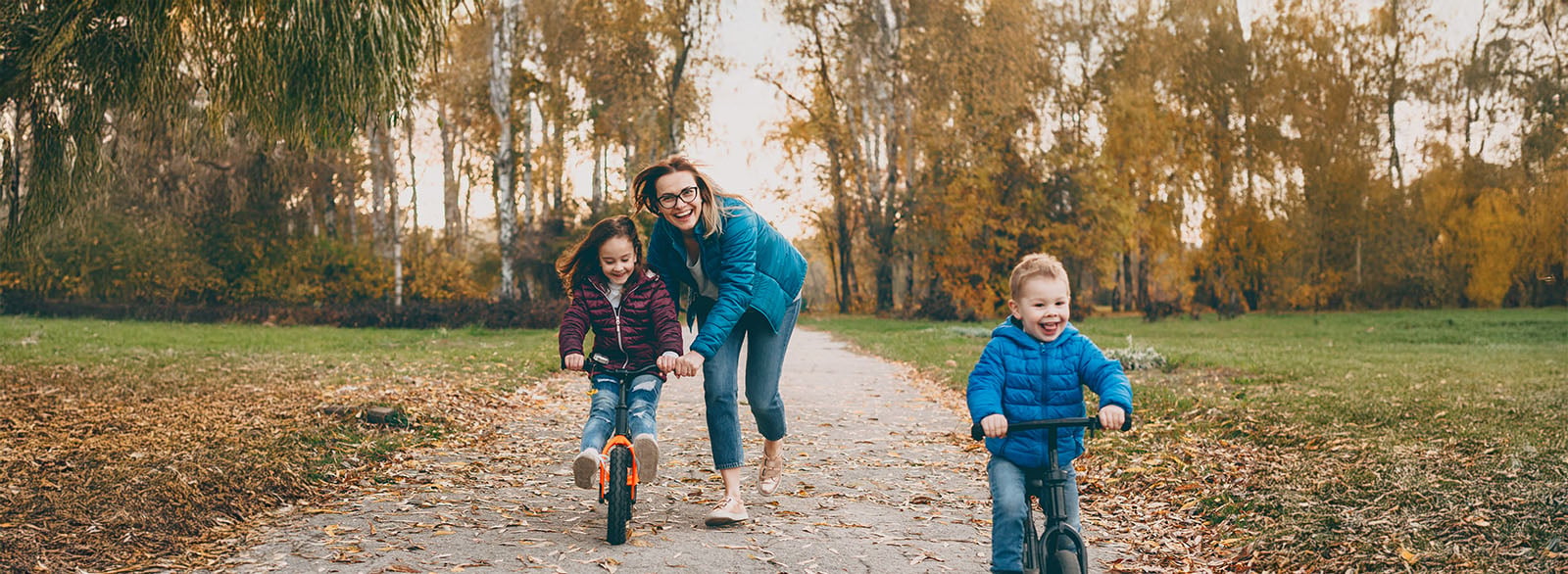 WhatEveryParentGuardianShouldKnowHero Mother playing with her daughter and son riding bicycles in a park.