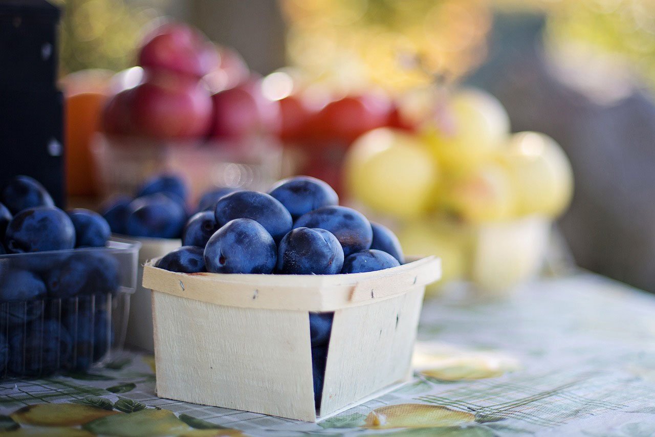 Carton of blueberries with other fruit  in the background.