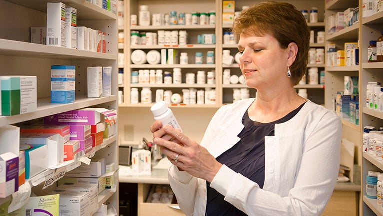 VIMCare pharmacist reading label on bottle of medicine
