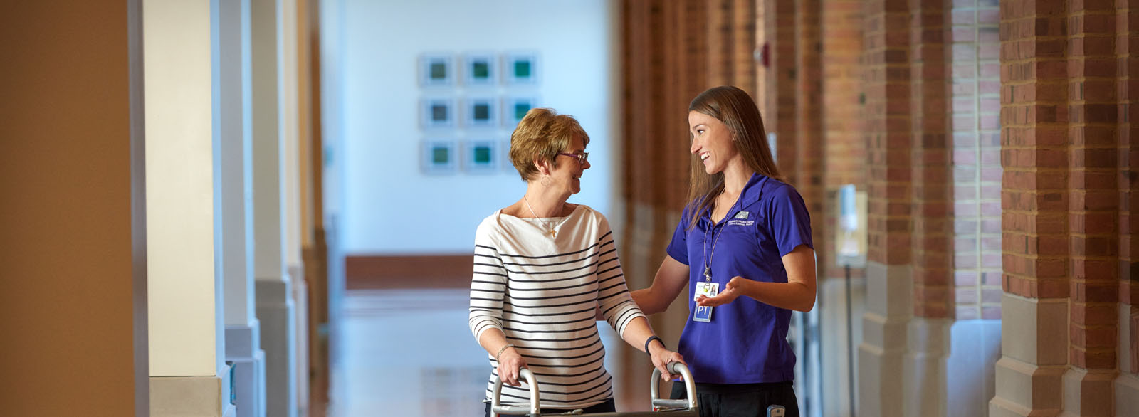 Physical therapist helping a patient use a walker in the South Gallery at Columbus Regional Hospital.