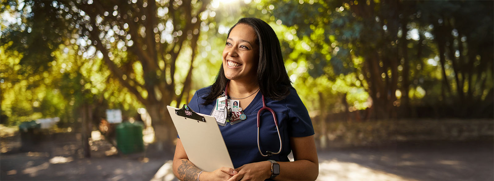 CRH nurse smiling holding clipboard outside on sunny day.